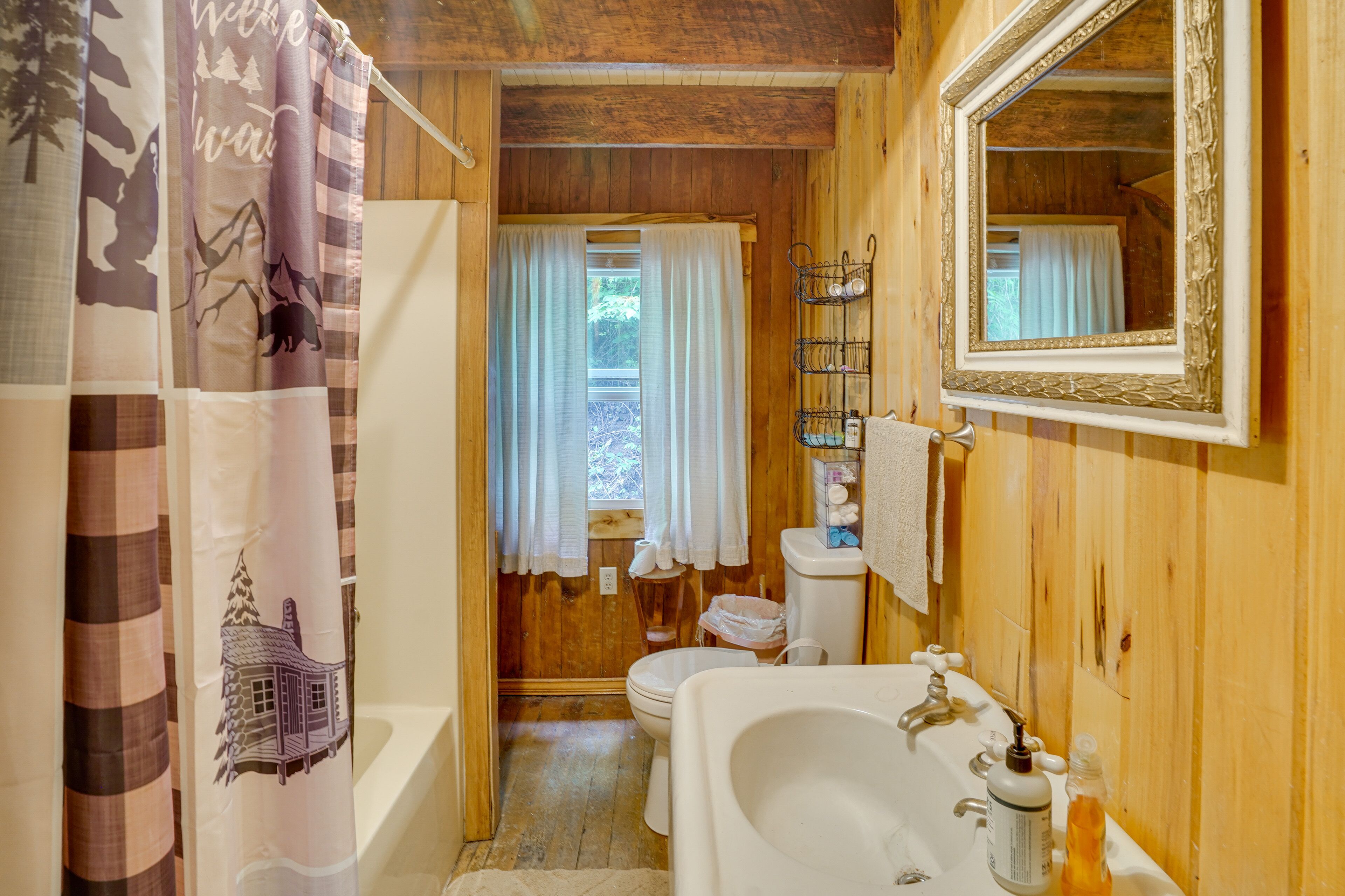 Ein Badezimmer einer Holzhütte mit Badewanne, Toilette und Waschbecken.