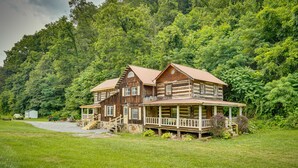 A large log cabin with a porch and multiple windows, surrounded by lush greenery. - Historic Cabin Retreat ~ 2 Mi to Seneca Rocks! (Seneca Rocks)