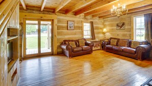 A log cabin interior with wooden floors, two leather sofas, a chandelier, and a television. - Historic Cabin Retreat ~ 2 Mi to Seneca Rocks! (Seneca Rocks)