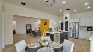 A modern kitchen with white cabinets, stainless steel appliances, and a dining area with a round table set for four. - 14 Mi to Dtwn: Tucson Escape w/ Patio! (Tucson)