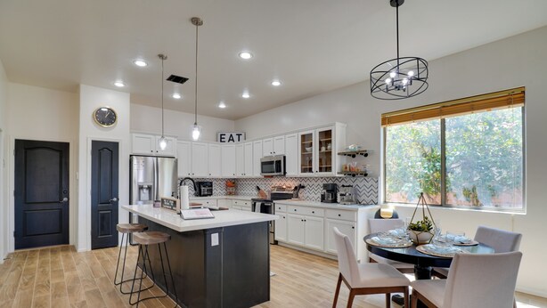 A modern kitchen with a central island, white cabinetry, and a dining area with a round table and chairs. - 14 Mi to Dtwn: Tucson Escape w/ Patio! (Tucson)