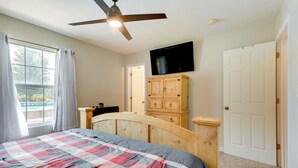 A bedroom with a bed, a ceiling fan, a TV mounted on the wall, a wooden dresser, and a door. - Cozy Stafford Home w/ Outdoor Pool: Pets Welcome! (Strafford)