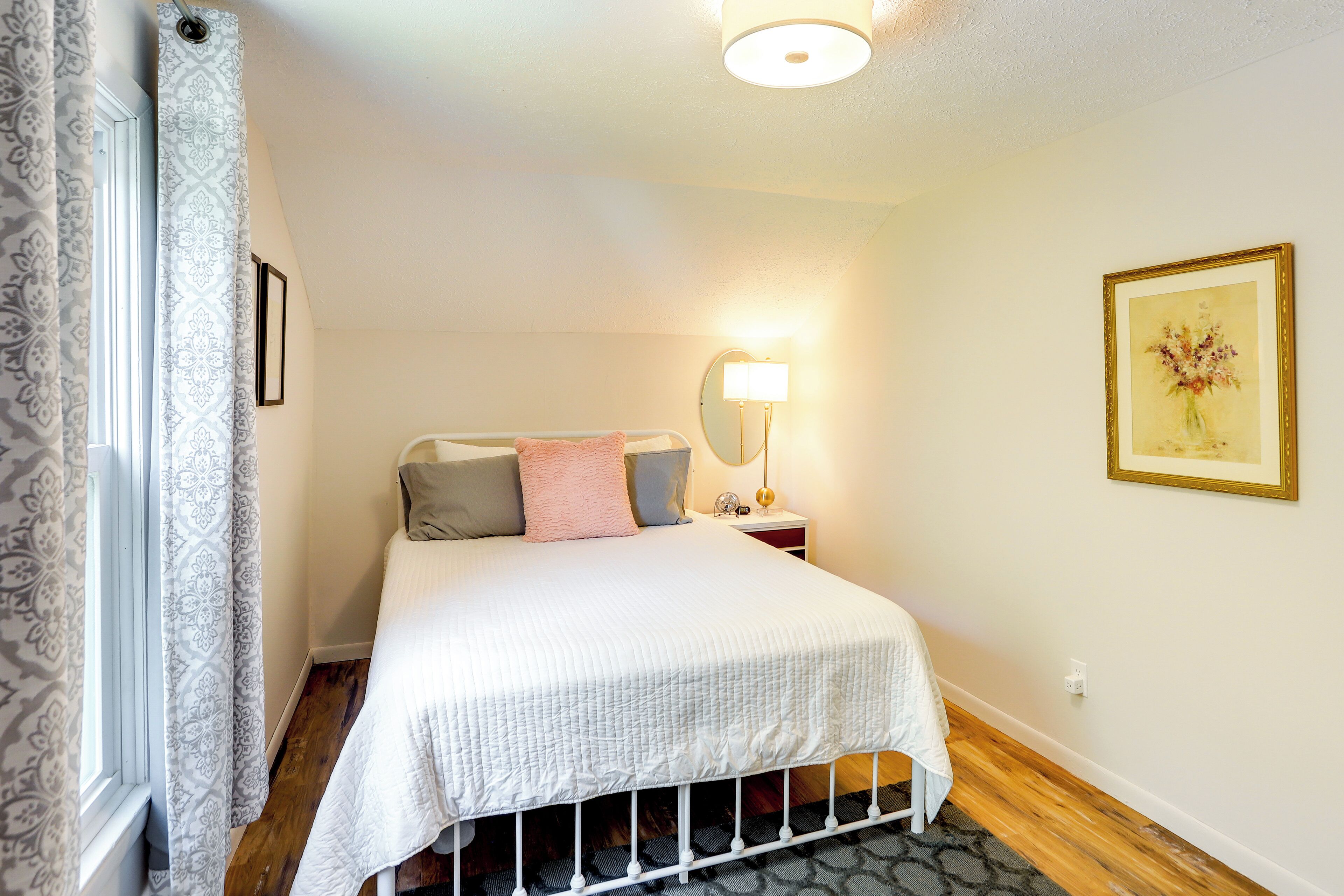 A bedroom with a bed, bedside lamp, and a framed picture on the wall.