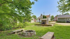 Ein Garten mit Feuerstelle, Picknicktisch und Gartenhaus.