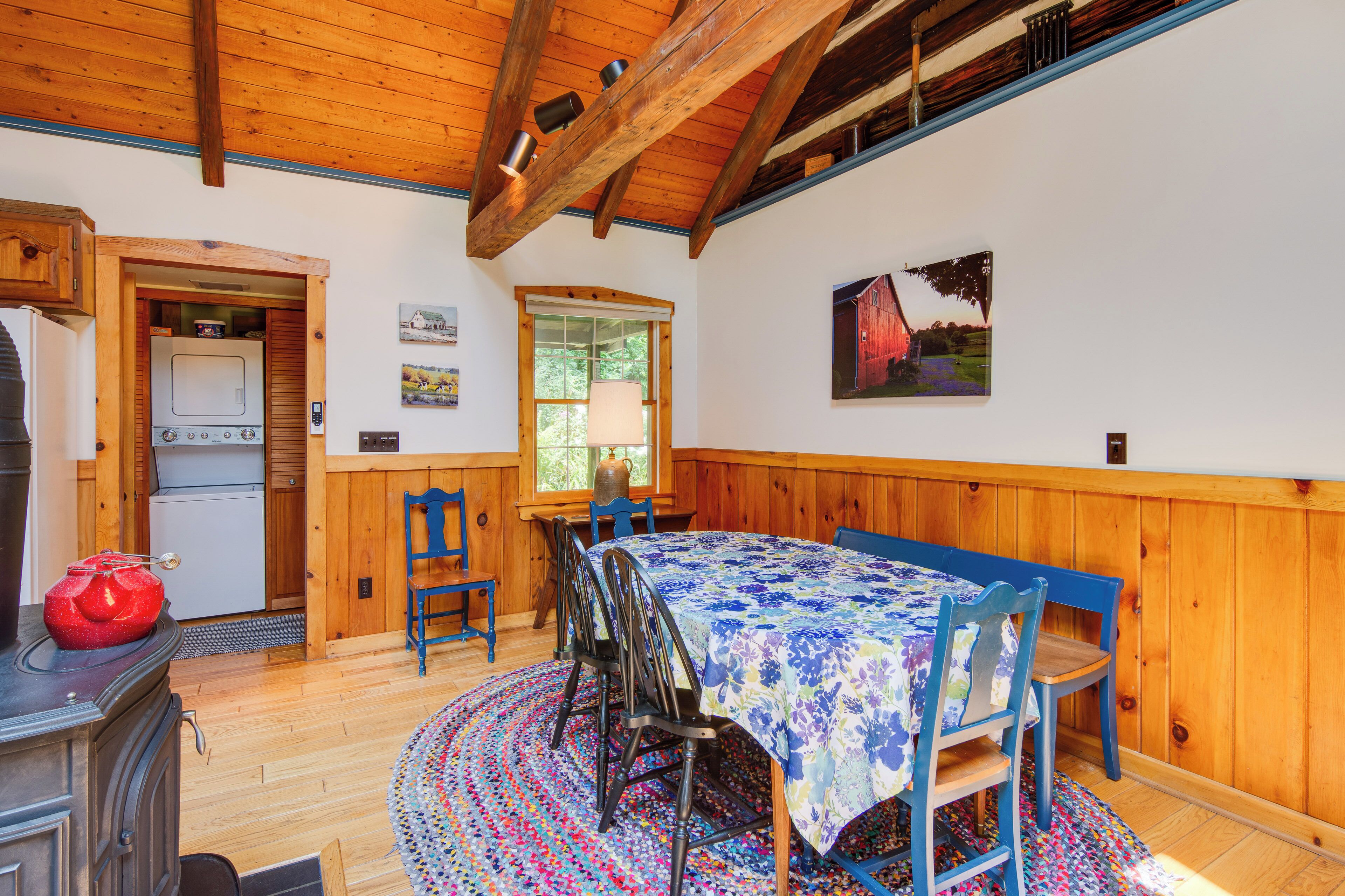 A wooden interior with a dining table, chairs, a stove, and a window.