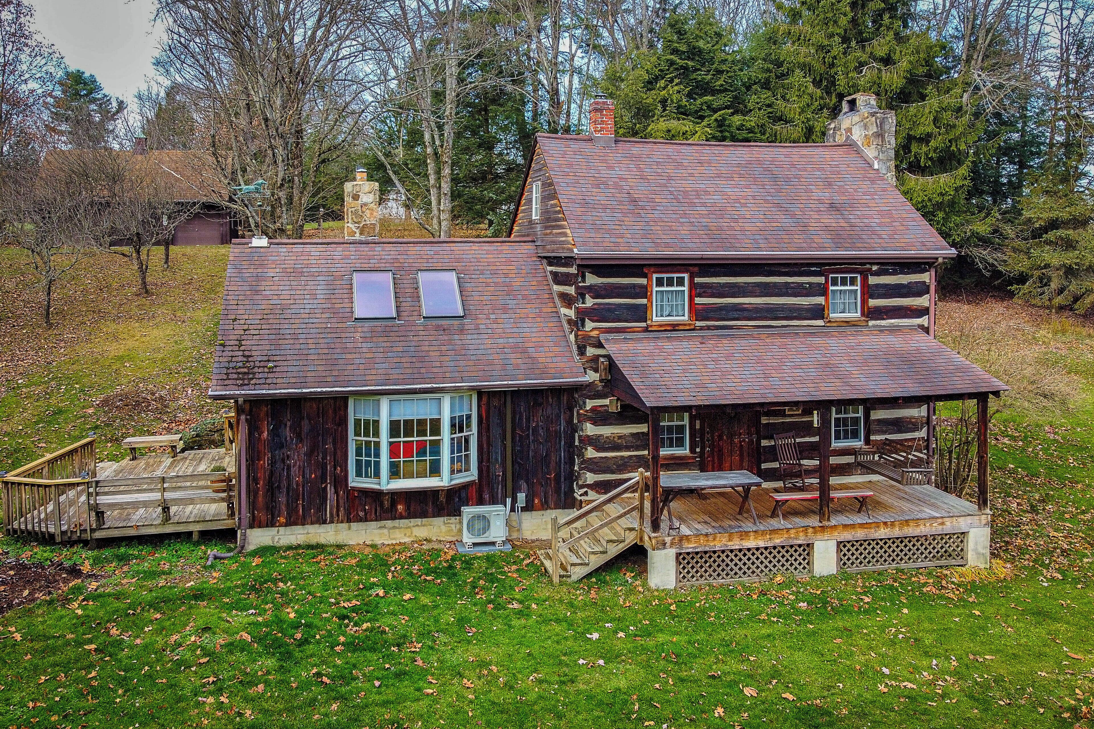 A log cabin with a porch, a chimney, and a small deck.