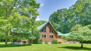 A log cabin with a green roof, surrounded by lush greenery and a clear sky. - Serene Valley Bend Cabin Rental: 7 Private Acres! (Beverly)