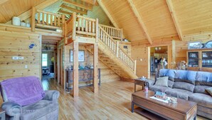 A spacious wooden cabin with a loft bedroom, a staircase, a living room with a sofa, and a dining area. - Serene Valley Bend Cabin Rental: 7 Private Acres! (Beverly)