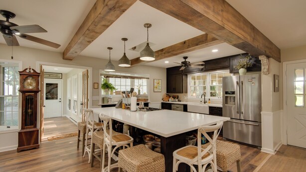 A spacious kitchen with a large island, wooden beams, and modern appliances. - Charming Villisca Getaway w/ Screened Porch! (Villisca)
