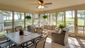 A sunroom with a ceiling fan, large windows, a dining table, and a sofa. - Charming Villisca Getaway w/ Screened Porch! (Villisca)
