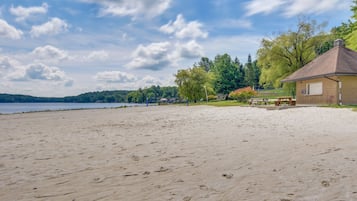Enjoy a serene beach setting with a small beach house surrounded by lush greenery and a tranquil body of water.