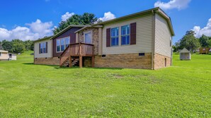 A single-story house with a stone foundation, a wooden deck, and a small attached garage. - Dog-friendly Home w/ Mtn Views in Chilhowie! (Chilhowie)