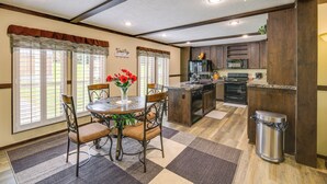 A kitchen with a central island, wooden cabinets, and a dining area with a table and chairs. - Dog-friendly Home w/ Mtn Views in Chilhowie! (Chilhowie)