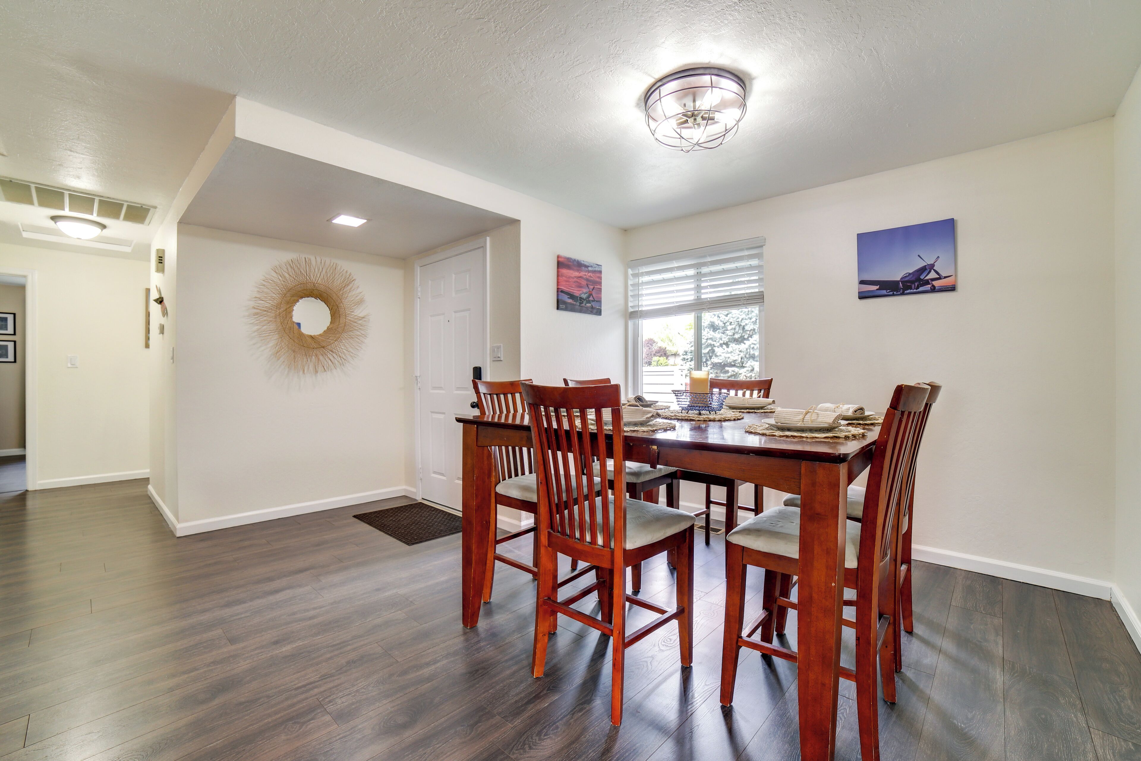 A dining area with a wooden table and chairs, a chandelier, and wall art.