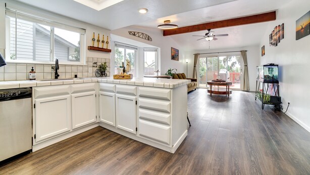 A spacious kitchen with white cabinetry, a dishwasher, and a wooden floor. - Pet-friendly Home w/ Hot Tub! 6 Mi to Dtwn Reno (Reno)