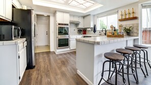 A modern kitchen with white cabinets, a black refrigerator, a built-in oven, and a large island with stools. - Pet-friendly Home w/ Hot Tub! 6 Mi to Dtwn Reno (Reno)