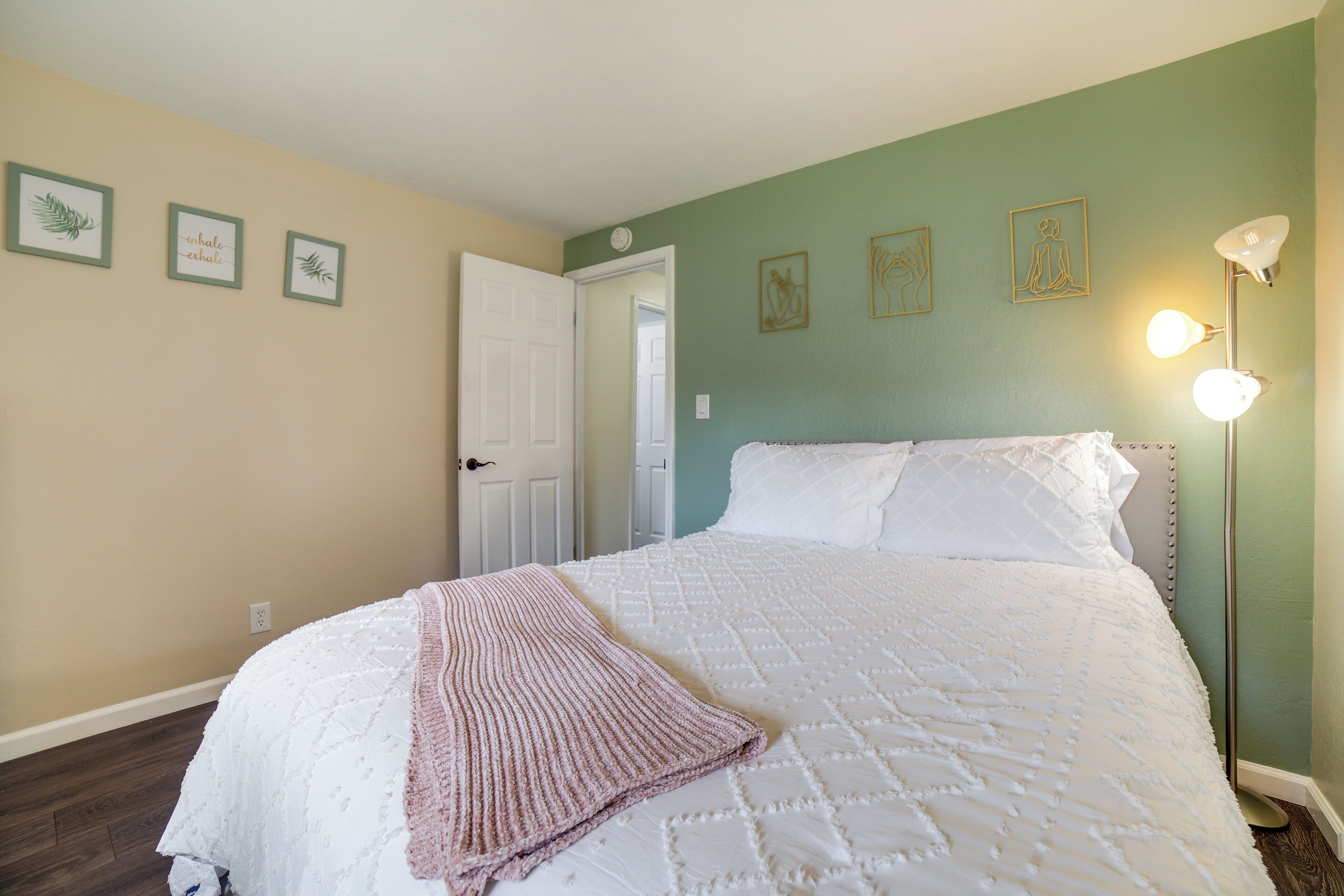 A bedroom with a bed, a door, and wall art.