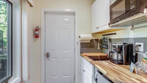 Una cocina compacta con una puerta blanca, un microondas, una cafetera y una encimera de madera.