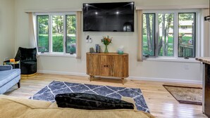 Una sala de estar con un televisor de pantalla plana colocado sobre un mueble de madera, un sofá azul y una alfombra estampada.