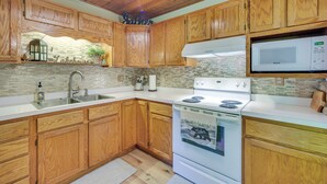 A kitchen with wooden cabinets, a white stove, and a microwave. - Grill & Fire Pit: Waterfront Cameron Retreat! (Cameron)