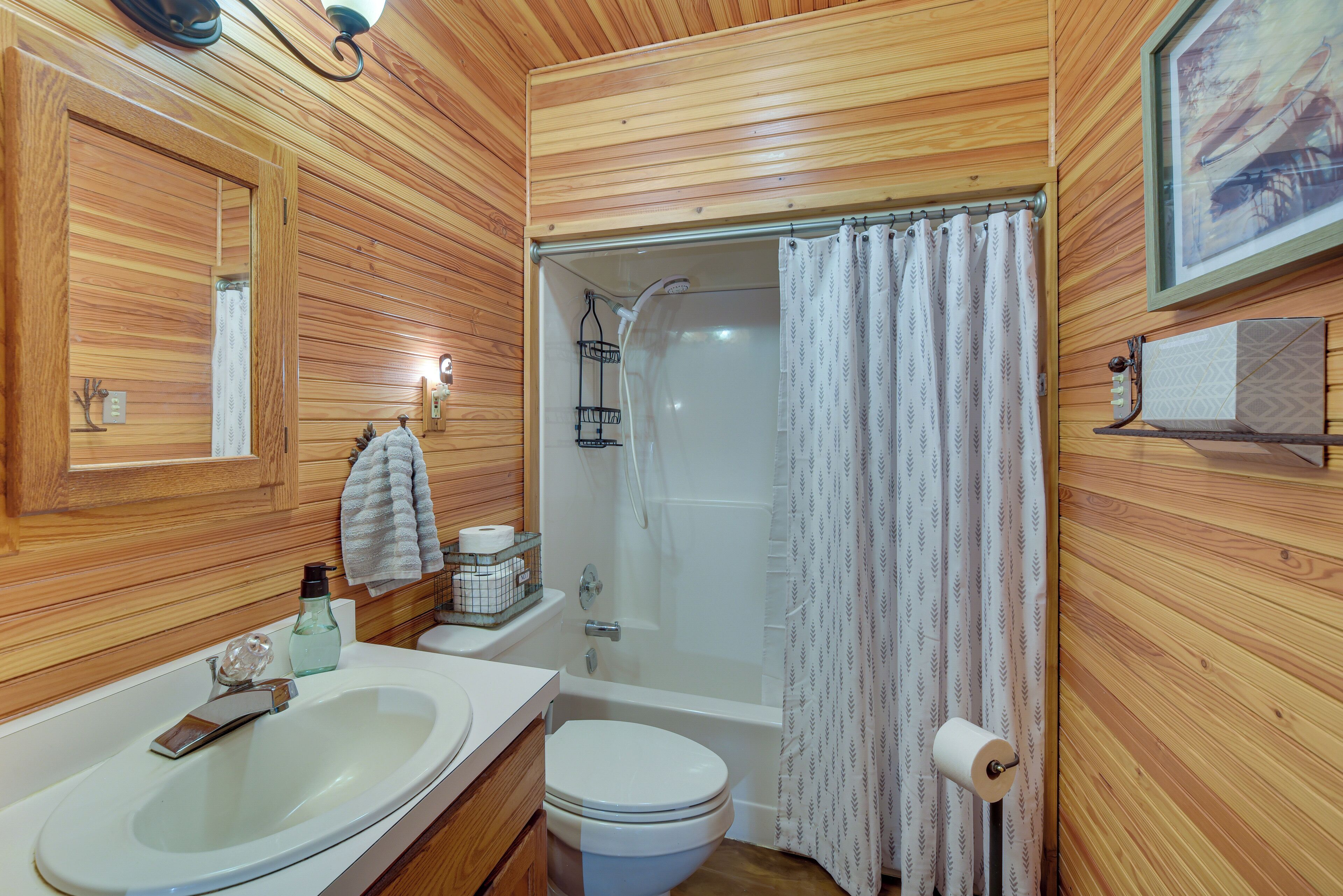 Een badkamer met houten lambrisering, een wastafel, toilet en douche.