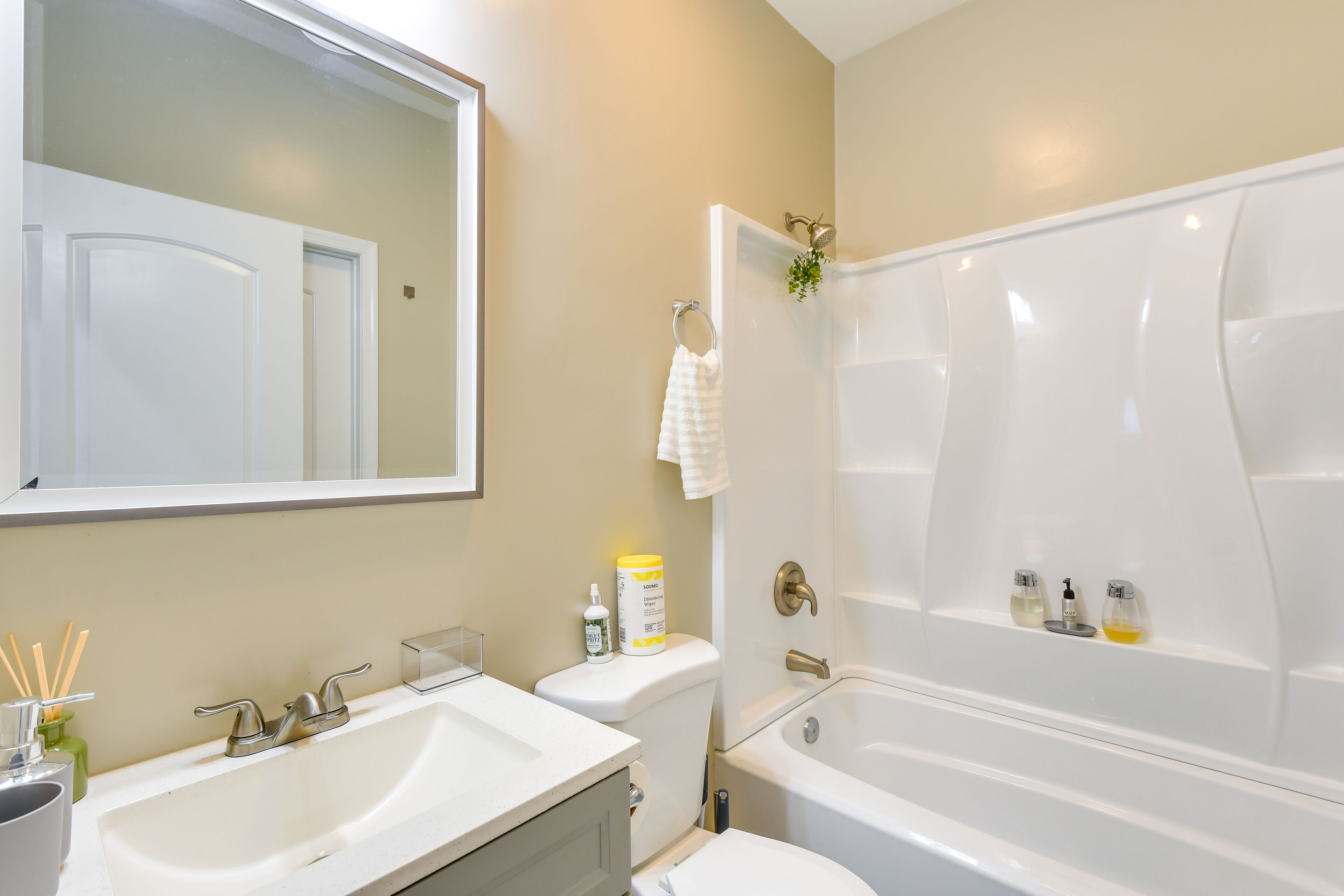 A bathroom with a white sink, toilet, and bathtub. There is a mirror above the sink and a towel hanging on the wall.