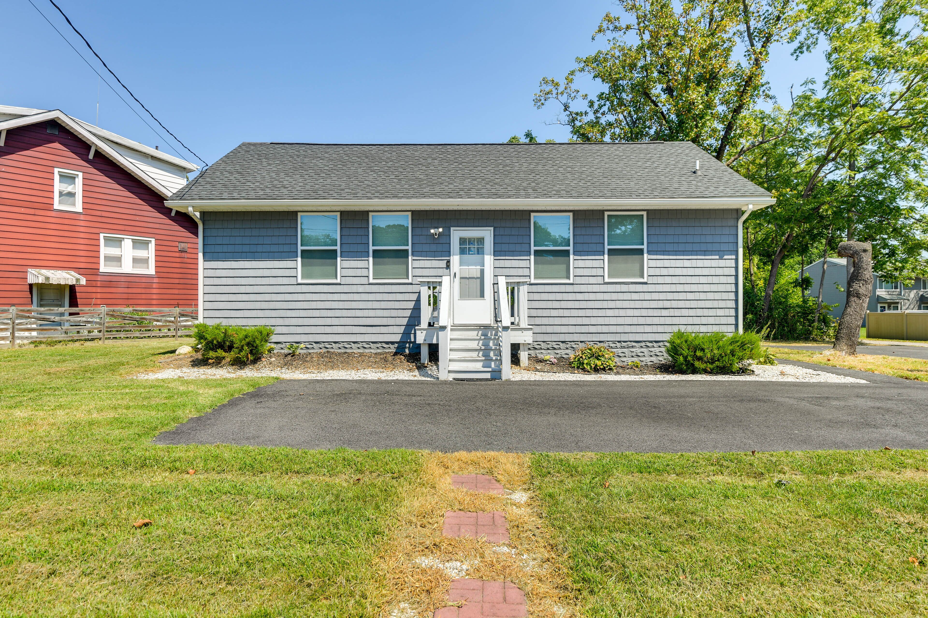 A single-story house with a gray exterior, a front porch, and a driveway leading to the entrance.