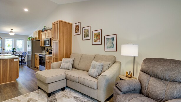 A modern living room with a sectional sofa, a gray armchair, and a kitchen in the background. - Wadena Vacation Rental ~ 1 Mi to Downtown! (Wadena)