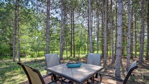 A wooden deck with a square table and four chairs, surrounded by tall trees. - Wadena Vacation Rental ~ 1 Mi to Downtown! (Wadena)