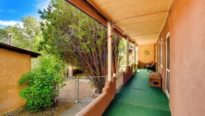 A covered outdoor corridor with a green floor, a wooden fence, and a building with a beige exterior.