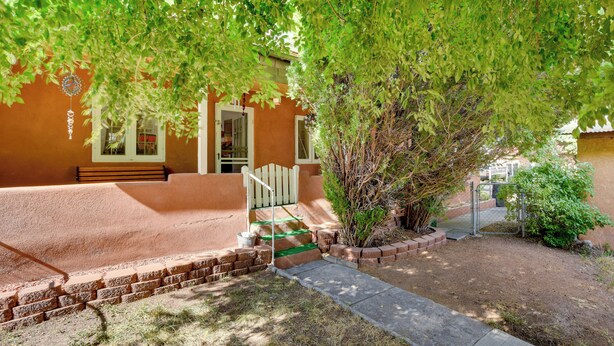 A house with a brick exterior, a front porch, and a tree providing shade.