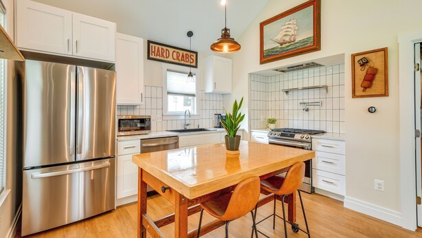 Una cocina moderna con electrodomésticos de acero inoxidable, una isla de madera y armarios blancos.