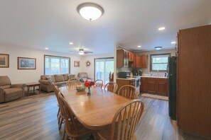 A spacious living room with a wooden dining table, comfortable seating, and a ceiling fan. - Riverfront Covington Cabin w/ Deck & Fire Pit! (Covington)