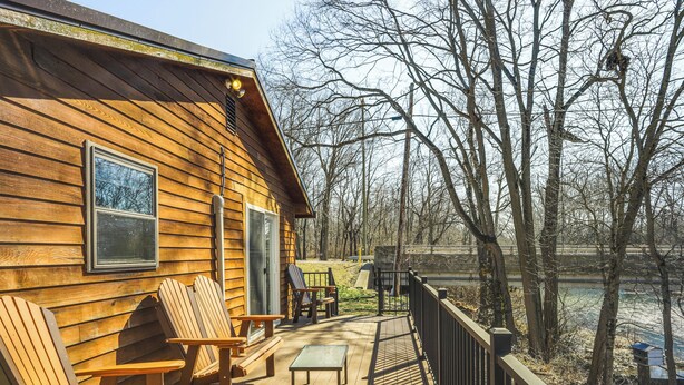 A wooden cabin with a deck, outdoor seating, and a view of a river. - Riverfront Covington Cabin w/ Deck & Fire Pit! (Covington)