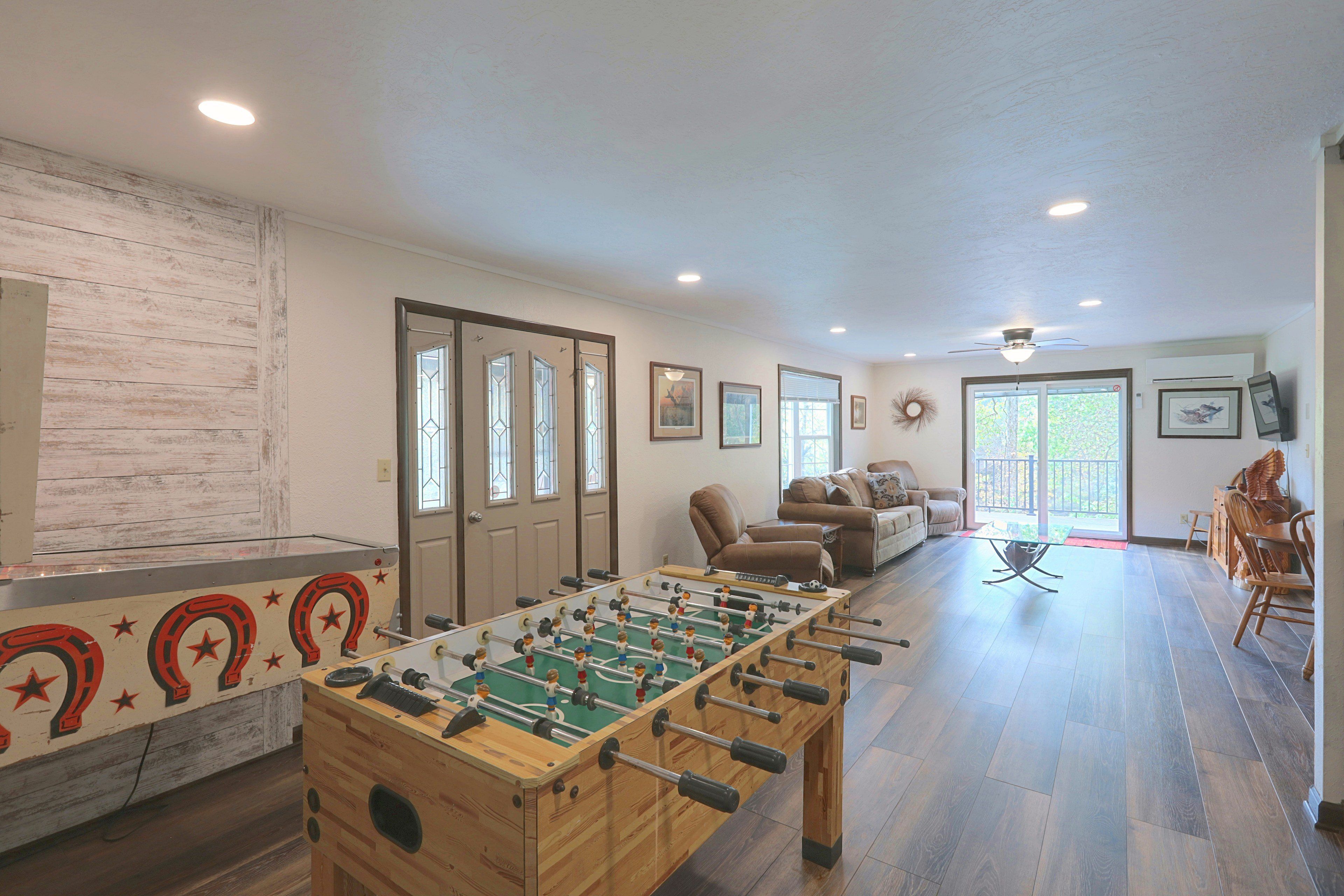 A spacious living area with a foosball table, a sofa, and a television.