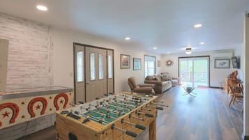 A spacious living area with a foosball table, a sofa, and a television.