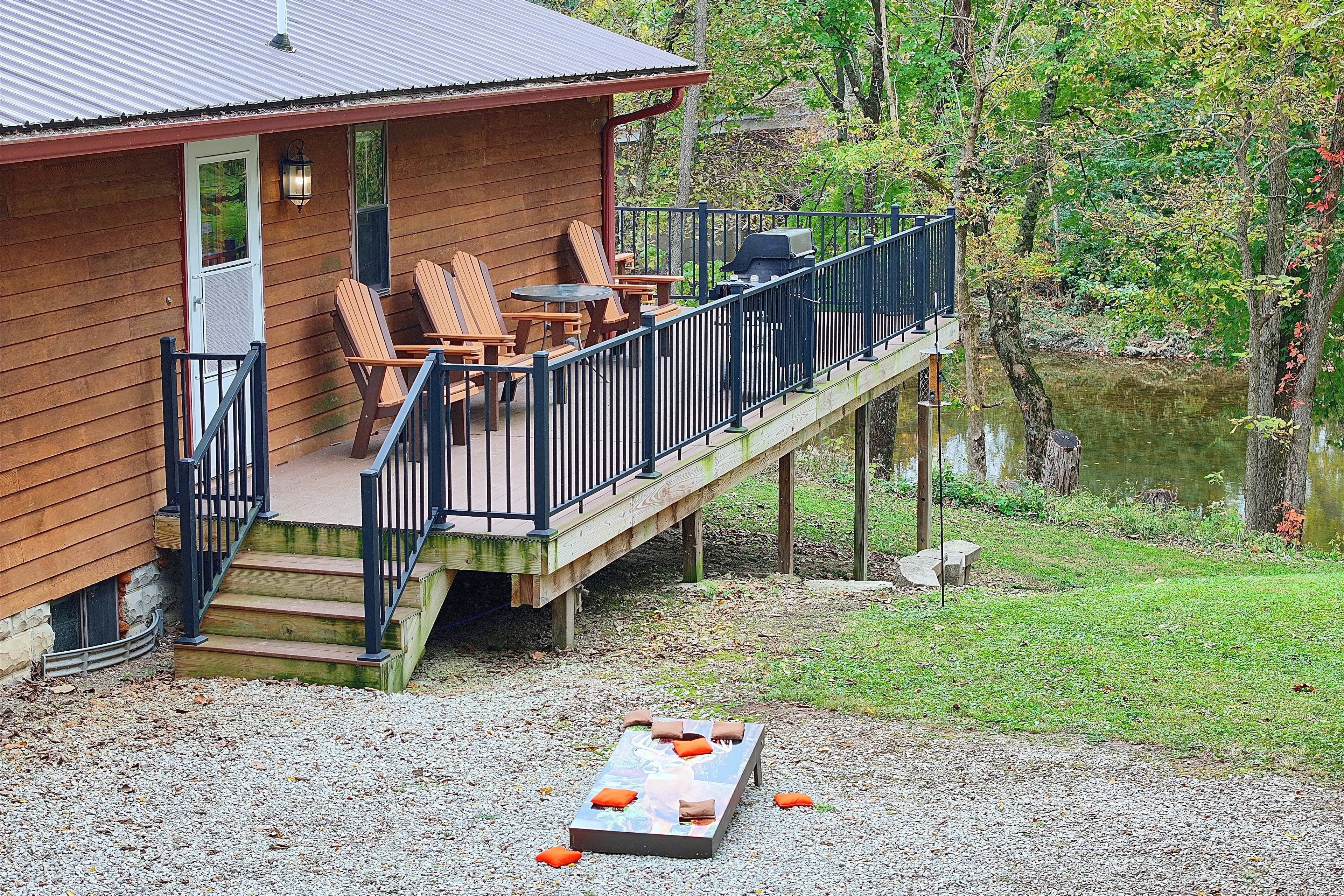 A wooden cabin with a deck, outdoor seating, and a view of a lake.
