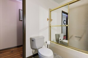 Een badkamer met toilet, spiegel en houten vloer.