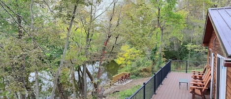 A wooden deck with outdoor furniture overlooking a body of water and dense foliage.