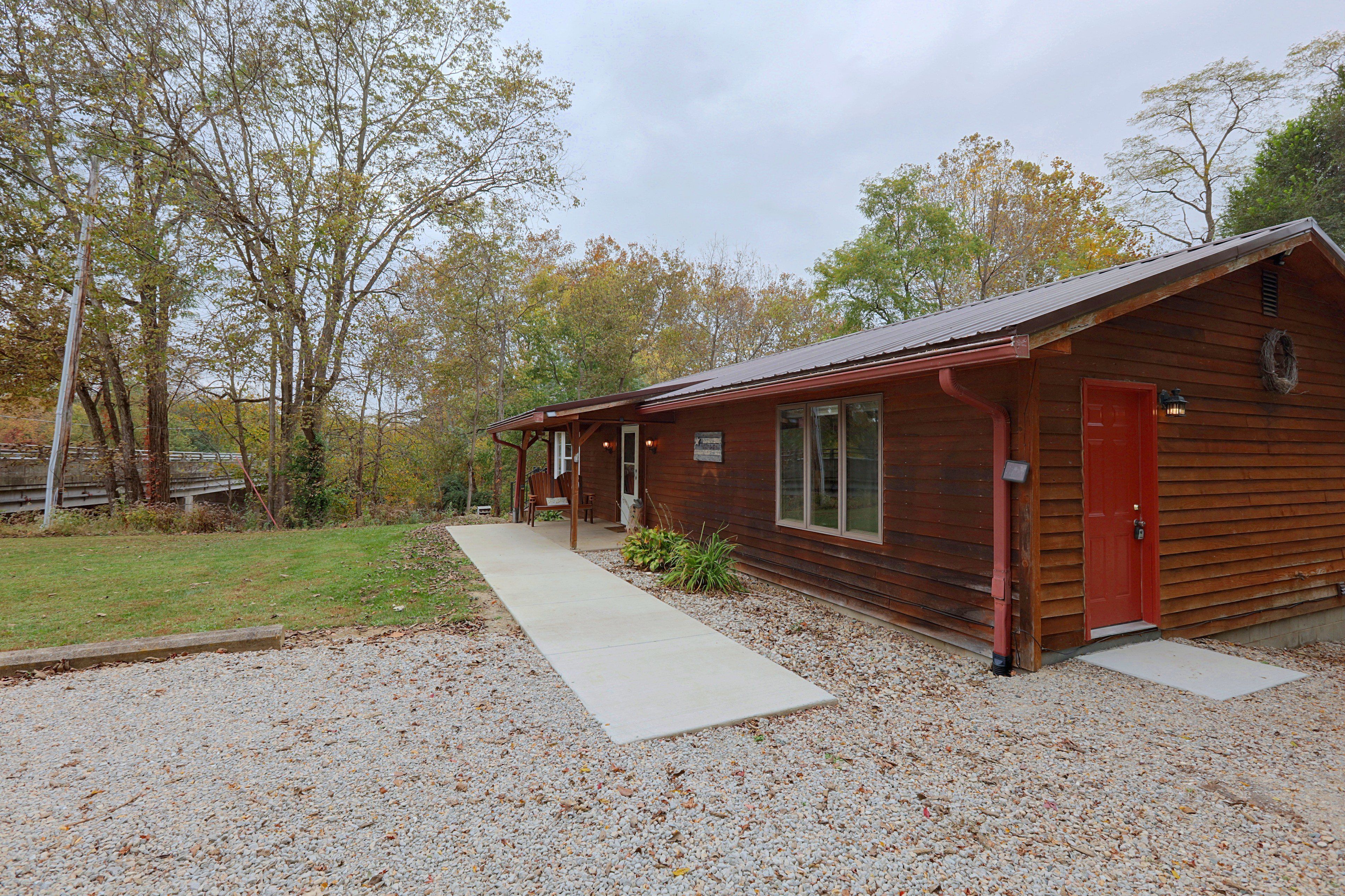 A wooden cabin with a gravel driveway and a covered porch.