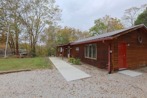 A wooden cabin with a gravel driveway and a covered porch.