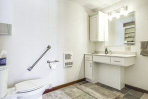 Een badkamer met een toilet, een wastafel met spiegel en een handgreep.