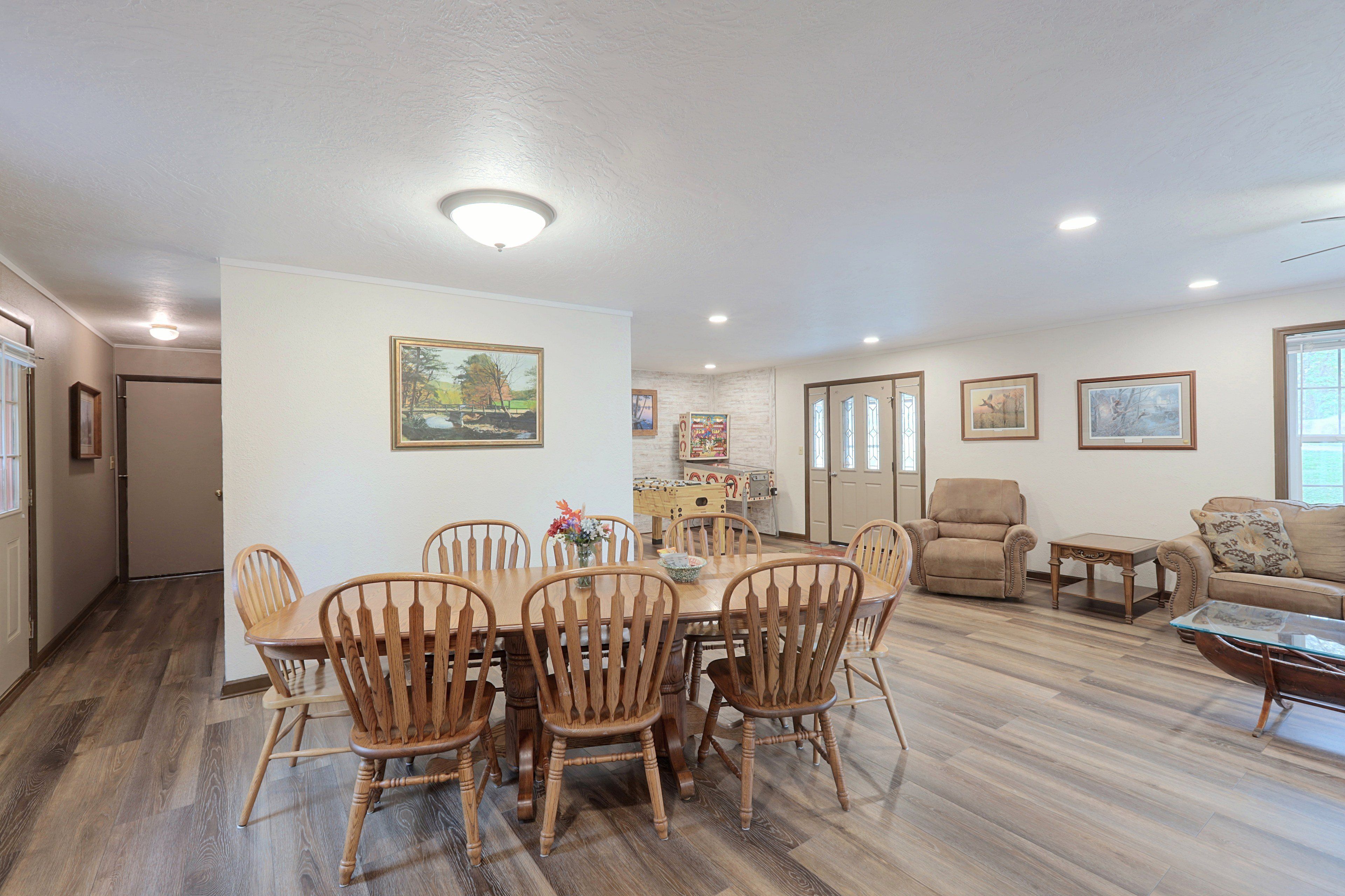 A spacious living room with a dining area, wooden furniture, and artwork on the walls.