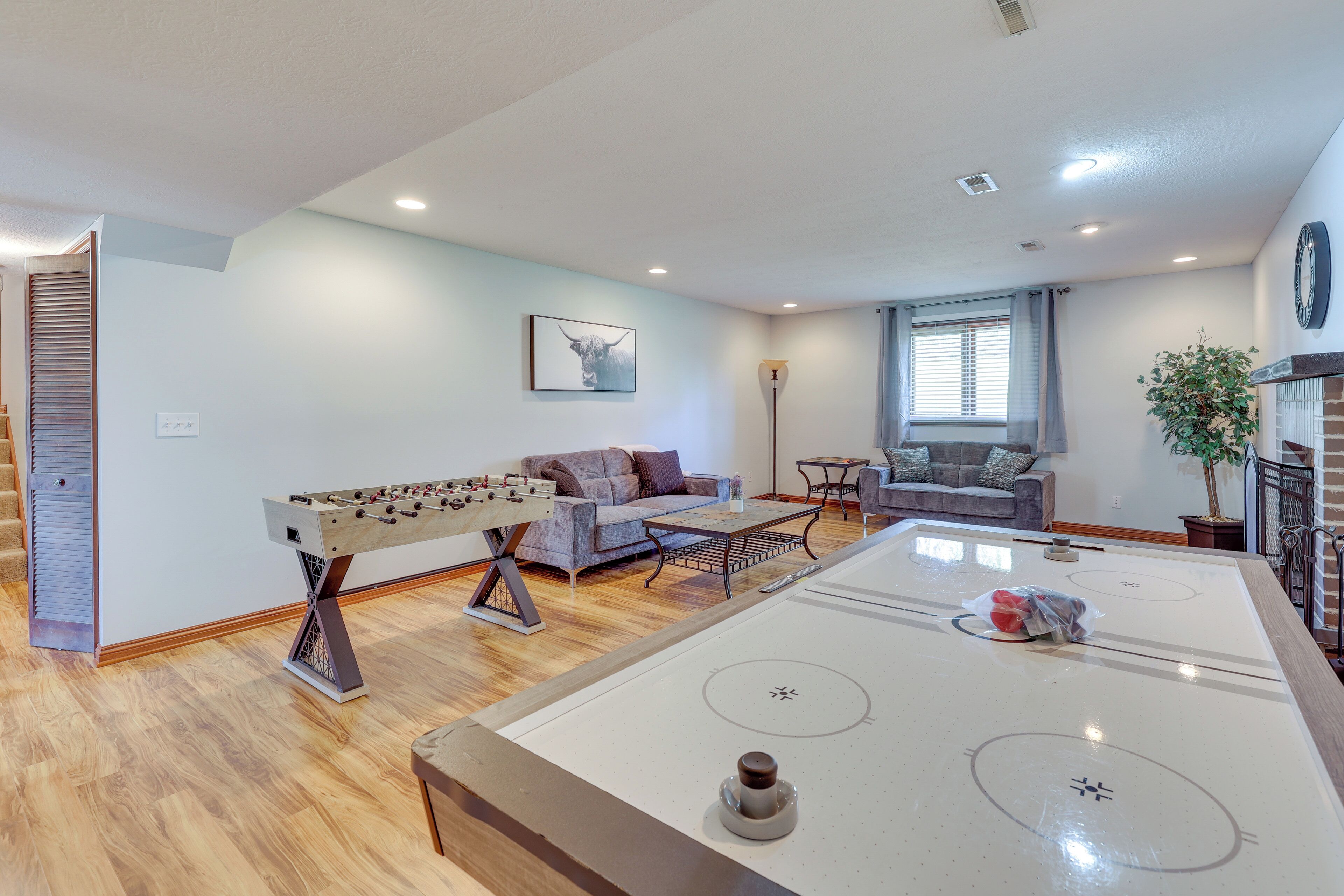 Una sala de estar con mesa de fútbol, sofá, mesa de centro y mesa de ping pong.