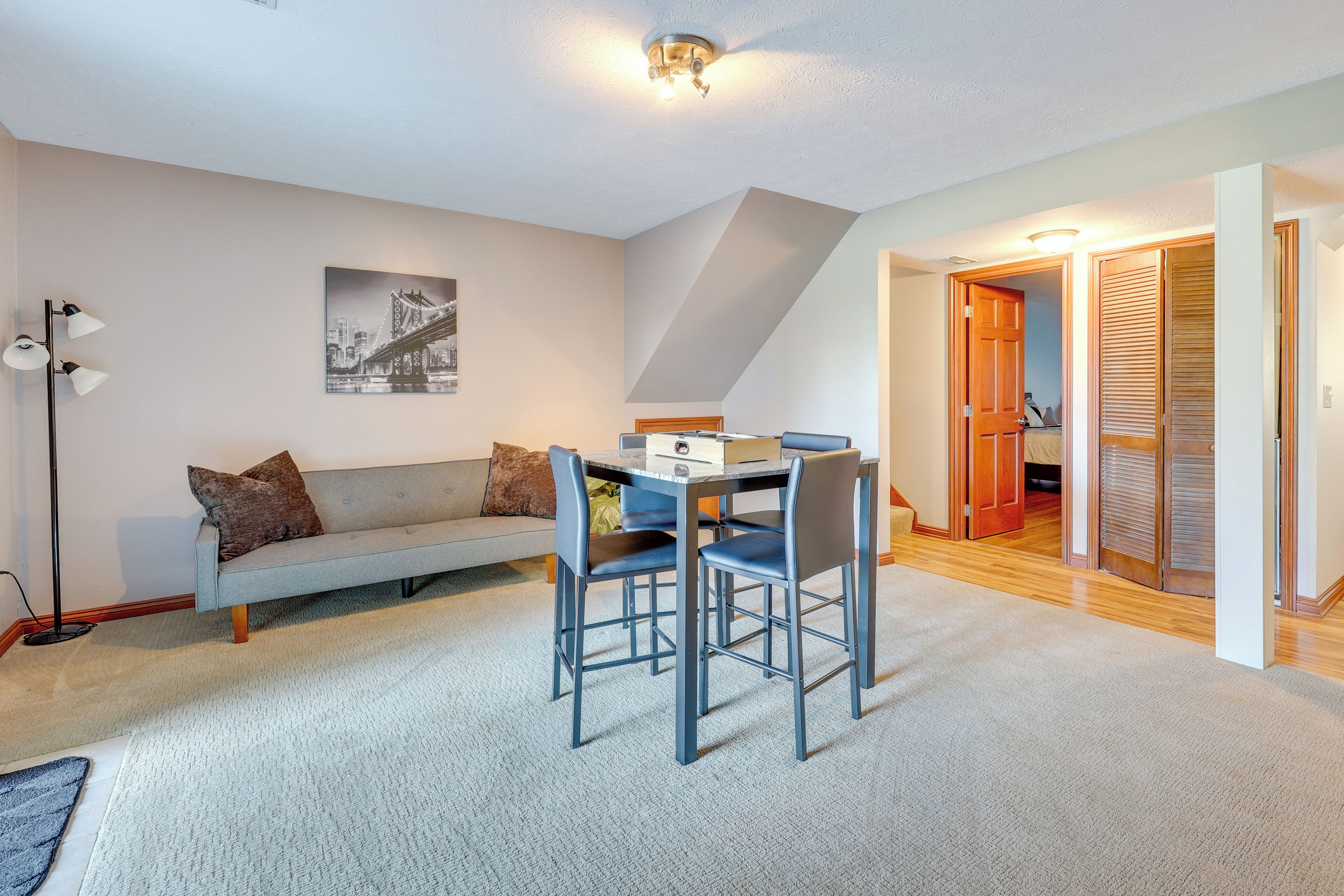 A modern living room with a sofa, a dining table with chairs, a floor lamp, and a ceiling light fixture.