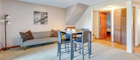 A modern living room with a sofa, a dining table with chairs, a floor lamp, and a ceiling light fixture.
