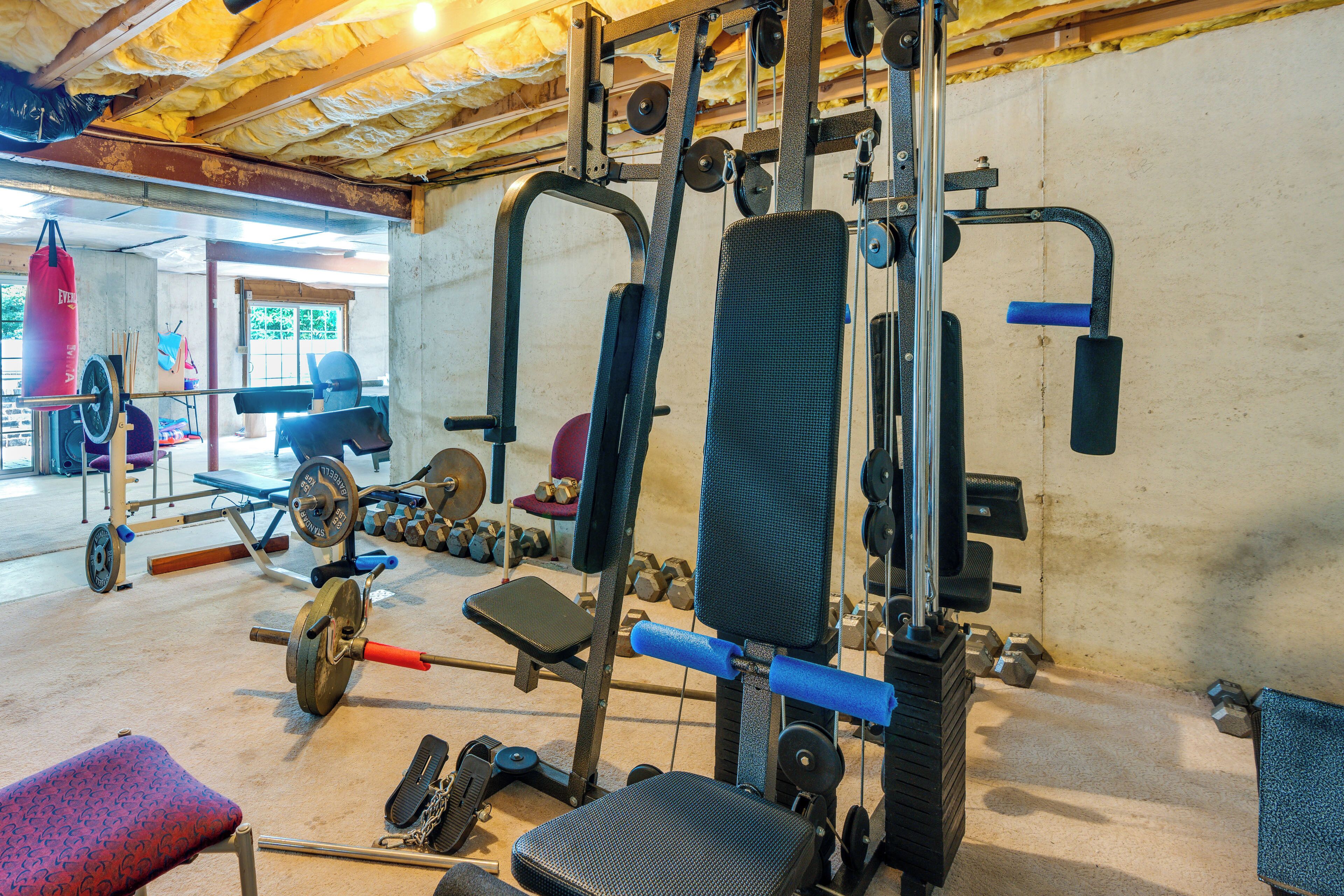 A gym with weightlifting equipment, benches, and dumbbells.