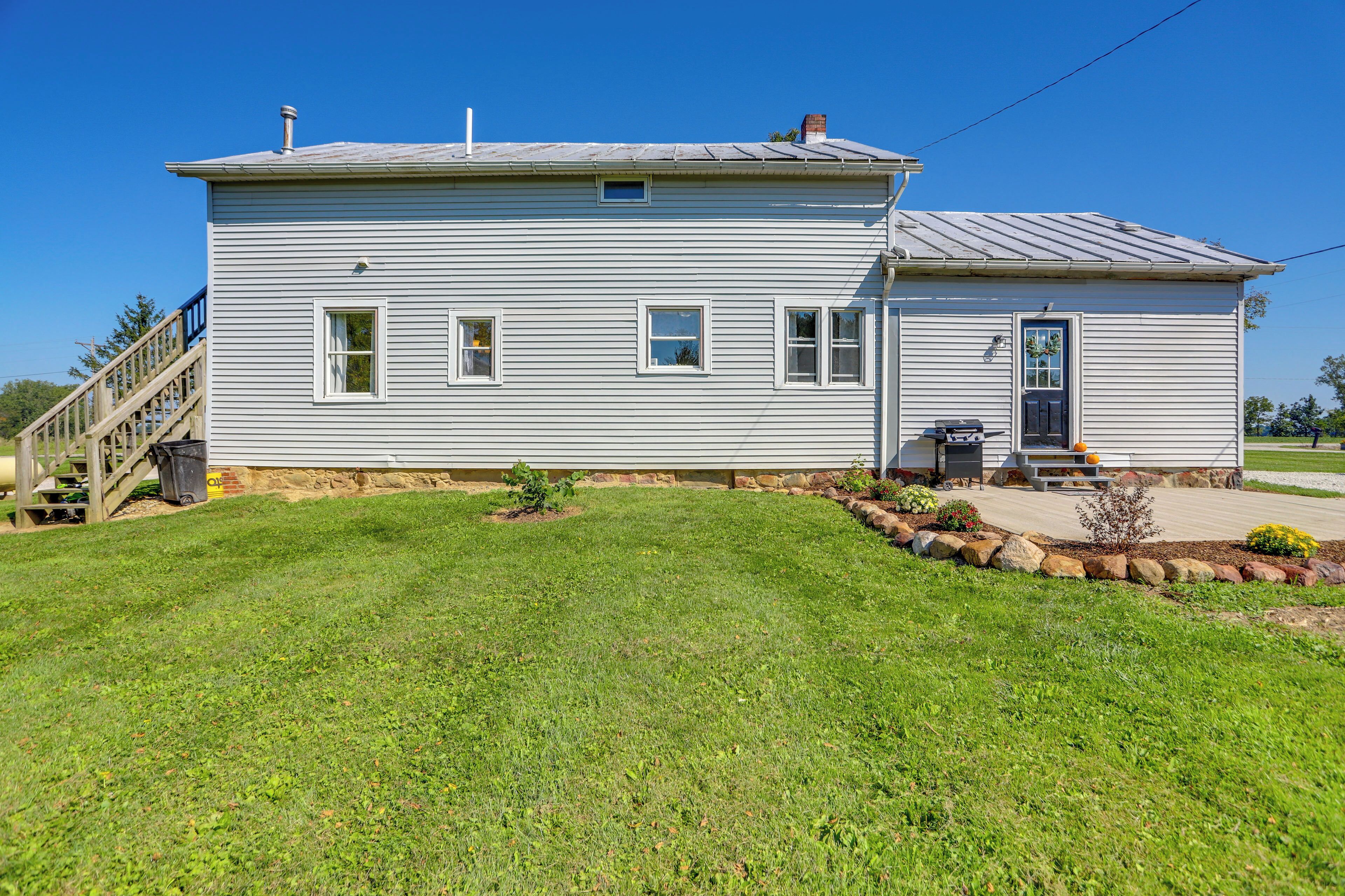 A single-story house with a front porch, a small front yard with a flower bed, and a staircase leading to a deck.