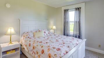 A neatly made bed with floral bedding, two bedside lamps, and a nightstand with a drawer.