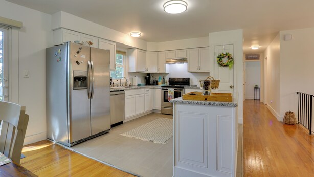 A modern kitchen with white cabinetry, stainless steel appliances, and a wooden dining table. - Kiamesha Lake Home w/ Deck: 4 Mi to Resorts World! (Kiamesha Lake)